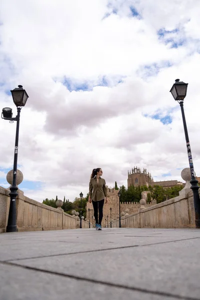 Young woman traveller walking through a bridge using a military green shirt