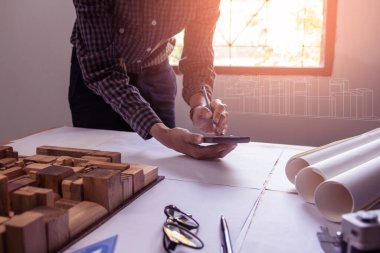 Hesap makinesi kullanarak adam elini kapat. Mimarlar, mühendisler ofiste bir planla birlikte çalışıyorlar, Vintage, Sunset Light. Seçici Odaklanma