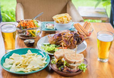  - Bira. Akşam yemeği kavramı, tavuk kızartması, salata, ahşap masada patates kızartması.
