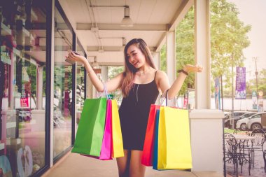 Mutluluk siyah elbiseli güzel Asyalı kadın gülümsüyor alışveriş merkezinde gün batımında alışveriş yaparken eğleniyorlar..