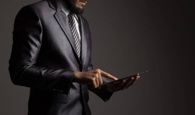 Kapatın. Gri takım elbiseli bir işadamının eli, cep telefonundan borsanın büyüme hızını kontrol ediyor.