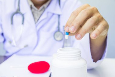 Sağlık ve tıbbi konsept. Üniformalı doktor hastanede beyaz ve mavi kapsül hapı tutuyor. Seçici odak