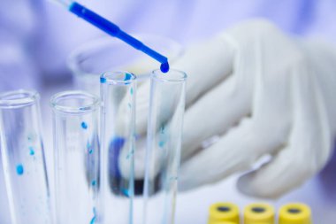 Kapatın. Laboratuvar araştırmalarında çalışan bir tıp çalışanı mavi sıvı olan Deneysel İlaç Tedavisi ile testler gerçekleştiriyor.