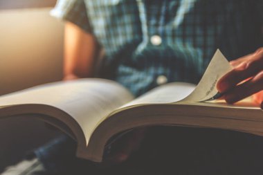 Man in green plaid shirt. Sitting on chair, Open book and reading . Sunset and instagram style filter photo vintage tone,Selective Focus