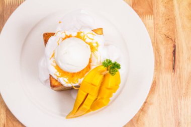 Lezzetli taze yumurta, kremalı tost ve kesilmiş mango.