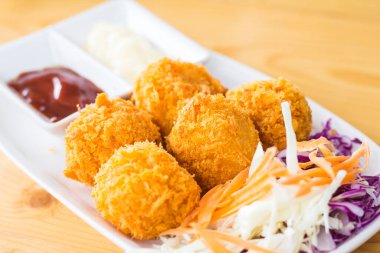 Tahta bir masaya yerleştirilmiş bir tabakta peynir topu..