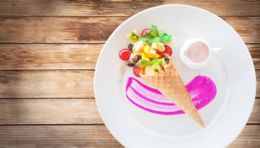 Ahşap arka planda dondurma külahında meyve salatası.