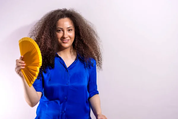 Afro girl smiling using a fan. Copy space on white background. Heat concept on white background