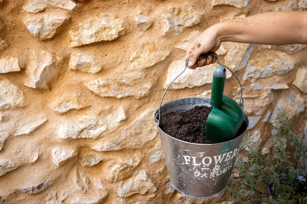 Woman\'s hand holding bucket of gardening soil. Elements of domestic gardening. Hard work concept.