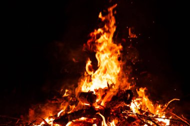 Yanan kırmızı kıvılcımlar gecenin büyük ateşinden yükselir. Yangın arka planda kıvılcım saçar. Soyut koyu parıltılı ateş parçacıkları ışıkları.