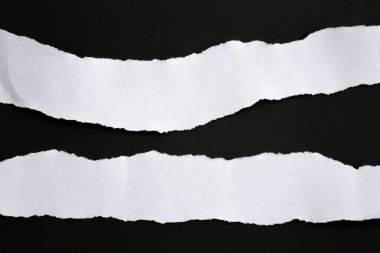 Siyah arka planda beyaz yırtık bir kağıt. koleksiyon kağıdı yırtılması