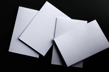 Boş maket kâğıdı. Broşür siyah masada, değiştirilebilir arka planda, beyaz kağıt koyu tonda izole edilmiş..