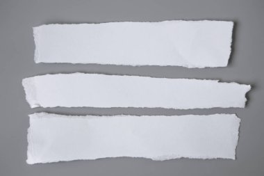 Gri arka planda beyaz yırtık kağıt. koleksiyon kağıdı yırtılması