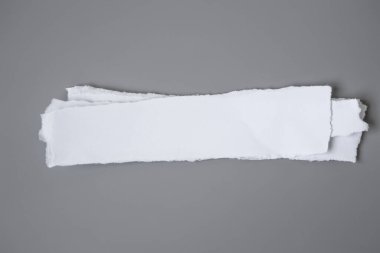 Gri arka planda beyaz yırtık kağıt. koleksiyon kağıdı yırtılması