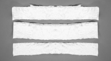 Gri arka planda beyaz yırtık kağıt. koleksiyon kağıdı yırtılması