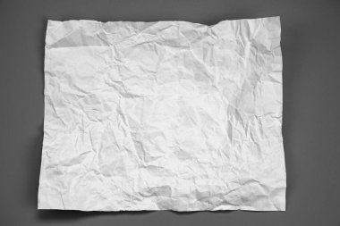 white and gray crumpled paper on  gray background. crush paper so that it becomes creased and wrinkled.