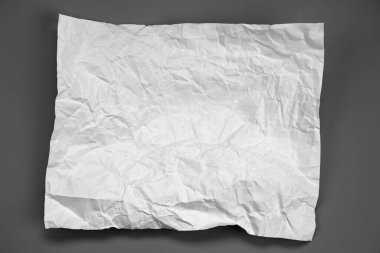 white and gray crumpled paper on  gray background. crush paper so that it becomes creased and wrinkled.