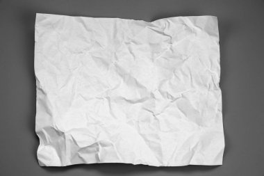 white and gray crumpled paper on  gray background. crush paper so that it becomes creased and wrinkled.