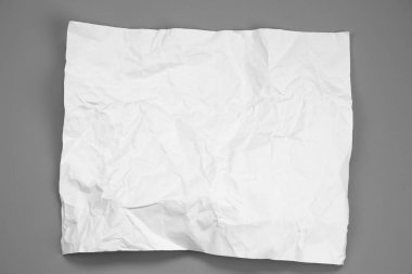 white and gray crumpled paper on  gray background. crush paper so that it becomes creased and wrinkled.