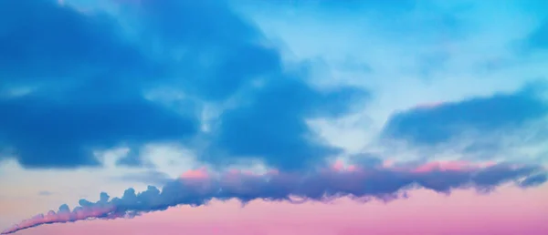 水平方向に広がる煙の噴煙と青紫色の明るいコントラストの曇りの空の背景 — ストック写真