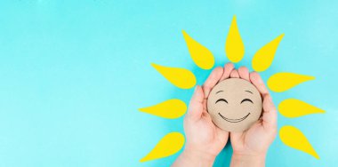 Holding a smiling face with yellow petals in the hands, mental health concept, positive mindset, support and evaluation symbol 