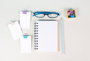 Blank notebook with a pen, paper and eyeglasses on a gray background, brainstorming for ideas, writing a message, workplace desk, home office