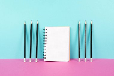 Empty notebook with a pencils on a pink and blue background, brainstorming for new ideas, writing a message, home office desk