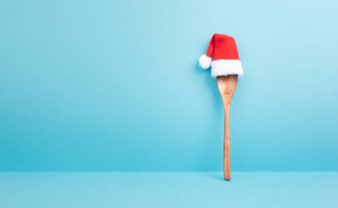 Tahta kaşıklı boş kağıt ve kırmızı Noel Baba şapkası, Noel tebrik kartı, tatil tarifi için fotokopi alanı.