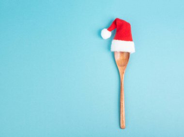 Tahta kaşıklı boş kağıt ve kırmızı Noel Baba şapkası, Noel tebrik kartı, tatil tarifi için fotokopi alanı. 