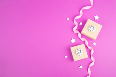 Küçük hediye kutuları, yıldızlar ve kurdeleler, pembe moda arka planlı Noel tatili 