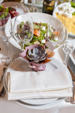 Düğündeki misafirler için hediye. Boş davetiye kartı ve tatlı sulu. Peçeteli, şarap bardaklı, tabaklı bir parti masası. Restorantta resepsiyon dekoru