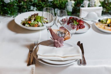 Düğündeki misafirler için hediye. Boş davetiye kartı ve tatlı sulu. Peçeteli, şarap bardaklı, tabaklı bir parti masası. Restorantta resepsiyon dekoru