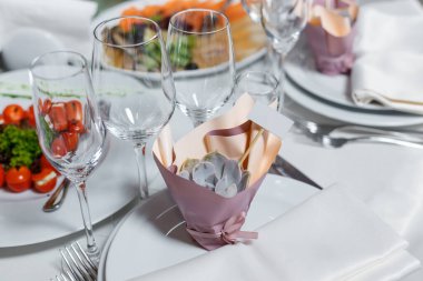 Düğündeki misafirler için hediye. Boş davetiye kartı ve tatlı sulu. Peçeteli, şarap bardaklı, tabaklı bir parti masası. Restorantta resepsiyon dekoru