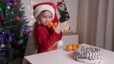 Kırmızı Noel Baba şapkalı komik çocuğun portresi portakalları elinde tutuyor.