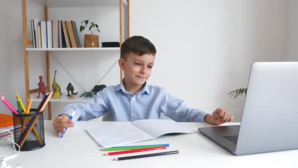Kid via laptop lytte lærer under online studere derhjemme. Elementær skole e-learning via videoopkald. Klog dreng gør lektier ved hjælp af internet og gadget. – Stock-video