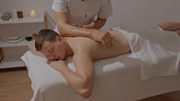 Profesionální masáž zad. Silný masér v uniformě dělá manuální terapii pro mladého muže. Odpočinek zad. Koncepce wellness, péče o tělo a zdraví — Stock video