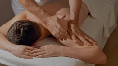Kaslı erkeklere yakın omuzlar masajı. Erkek eller SPA salonunda ya da klinikte profesyonel masaj yapıyor. Vücut ve sağlık hizmetleri kavramı, alternatif tıp