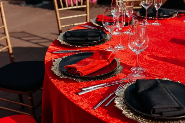 客人餐桌设置为黑色,红色和金色风格的宴会.精致奢华的晚餐布置：装饰、桌布、盘子、眼镜、餐巾、餐具。生日或婚宴的主题 — 图库照片