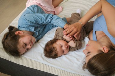 Çekici mutlu anne iki kızıyla yatıyor. Küçük kız. Mutlu aile