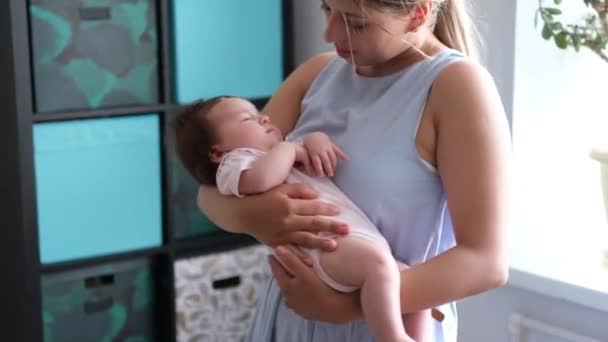 Atractiva madre feliz sosteniendo pequeña niña. Familia feliz — Vídeos de Stock