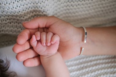 Anneler küçük bebeklerin elini tutarlar. Mutlu aile