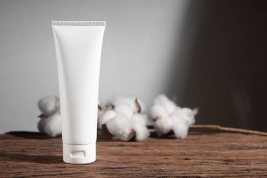 Pamuk çiçekli beyaz ahşap masa arka planı, kozmetik makyaj şişesi losyon kremi ürünleri güzellik moda cilt bakım modelleri.