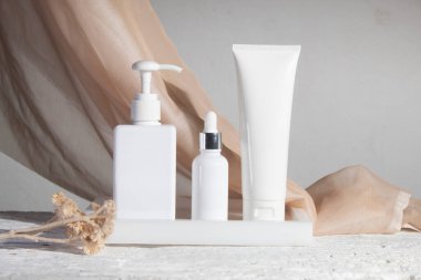 Kumaş tekstil, kozmetik makyaj şişesi losyon kremi ile beyaz ahşap masa arkası güzellik moda cilt bakım modeli