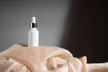 Kumaş tekstil, kozmetik makyaj şişesi losyon kremi ile beyaz ahşap masa arkası güzellik moda cilt bakım modeli