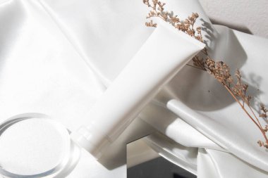 Yaşam tarzına sahip beyaz kumaş tekstil arka planı, kozmetik makyaj şişesi losyon kremi ürünü güzellik moda cilt bakım modeli.