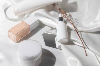 Yaşam tarzına sahip beyaz kumaş tekstil arka planı, kozmetik makyaj şişesi losyon kremi ürünü güzellik moda cilt bakım modeli.