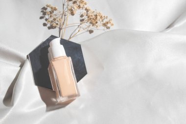 Yaşam tarzına sahip beyaz kumaş tekstil arka planı, kozmetik makyaj şişesi losyon kremi ürünü güzellik moda cilt bakım modeli.