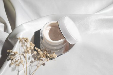 Yaşam tarzına sahip beyaz kumaş tekstil arka planı, kozmetik makyaj şişesi losyon kremi ürünü güzellik moda cilt bakım modeli.