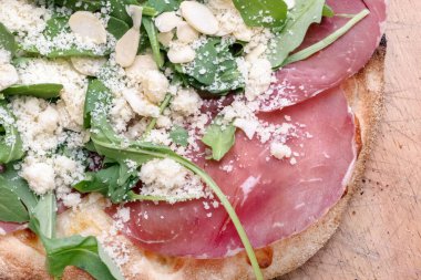 Mozzarella, roket, bresaola, parmesan ve bademli gurme pizza. Üst görünüm.