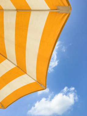 Güneşli bir günde sarı plaj şemsiyesi. Kumsalda parlak renkli şemsiye.